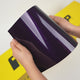 Hands holding Silent Purple (GAL34-HD) TeckWrap vinyl wrap sample with glossy finish