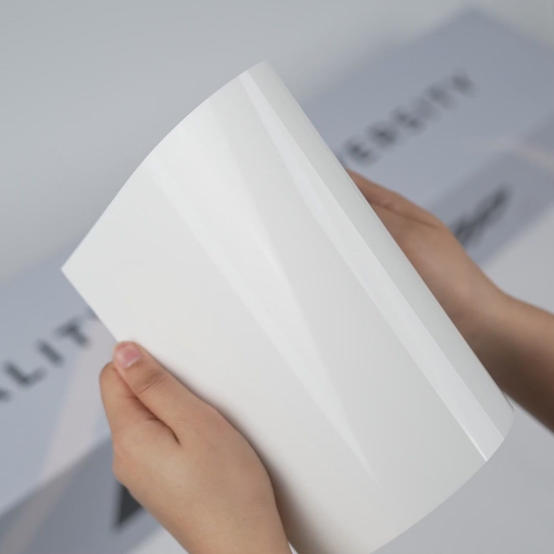 Hands holding a TeckWrap Pure White Gloss Color PPF sample (CPX302), showcasing its clean glossy pure-white finish and premium paint protection surface.