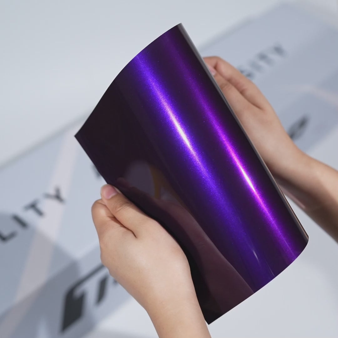 Hands holding a glossy Deep Amethyst Purple TeckWrap Color PPF sheet (CPX602), showcasing the luxury high-gloss finish of the premium paint protection film.