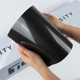 TeckWrap A5 Paint Protection Film sample in glossy smoke black with mirror-like reflections on the curved sheet