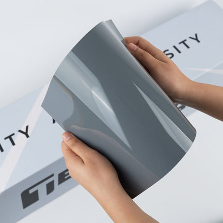 Pale grey TeckWrap A5 Pure Color Paint Protection Film sample held in hands