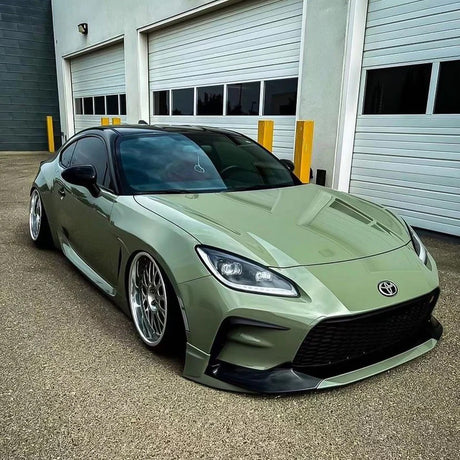 Front-side view of Toyota GR86 wrapped in TeckWrap Moss Green CG23-HD Glossy Vinyl, highlighting aggressive styling and smooth olive tone.