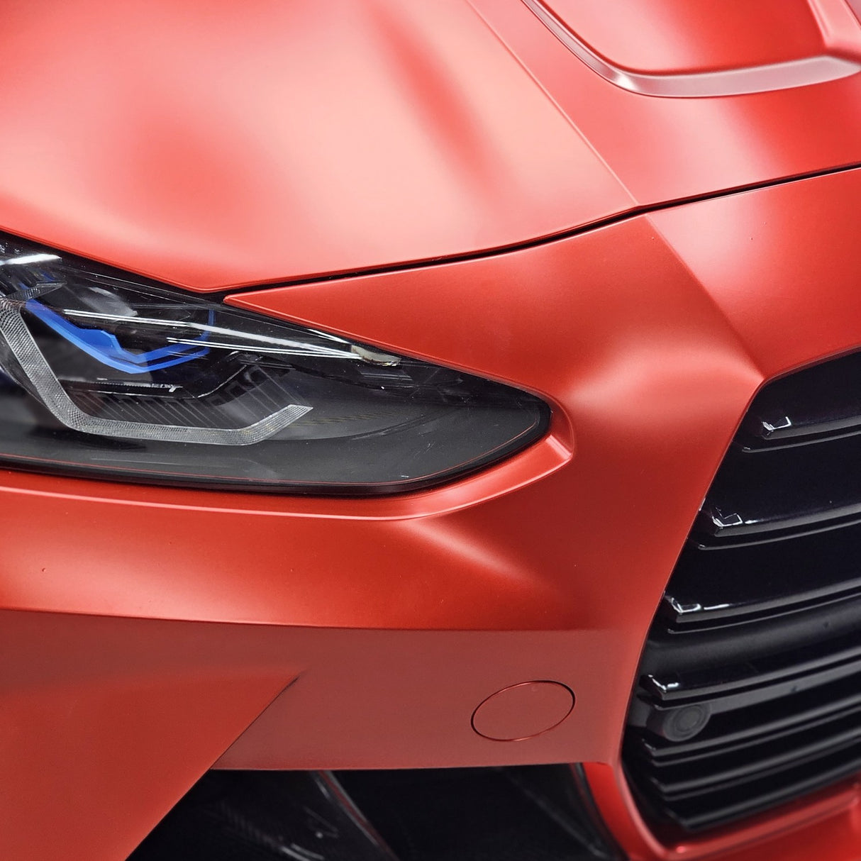 TeckWrap Satin Crimson Red vinyl (VCH401-S) wrapping cleanly around the headlight of a BMW M4