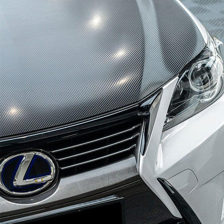 Front hood detail of a car wrapped in TeckWrap Pitch Black Carbon (CF02), illustrating the luxurious and realistic carbon fiber texture under light reflection.